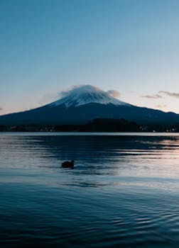Capture the tranquility of Mount Fuji reflected in a calm lake at twilight.