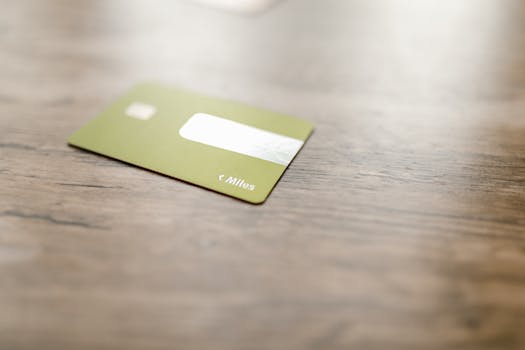Green credit card placed on a wooden surface, captured with a blurred focus for a modern, minimalistic feel.